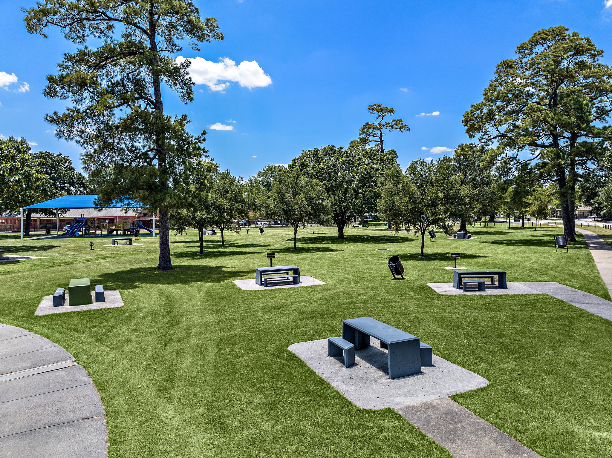 Finnigan Park with green grass, tall trees, and a playground